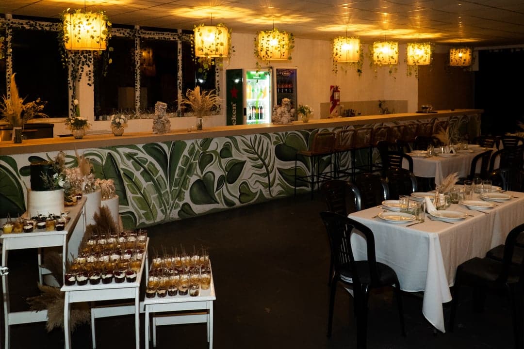 Salón de noche con mesa dulce y barra iluminada